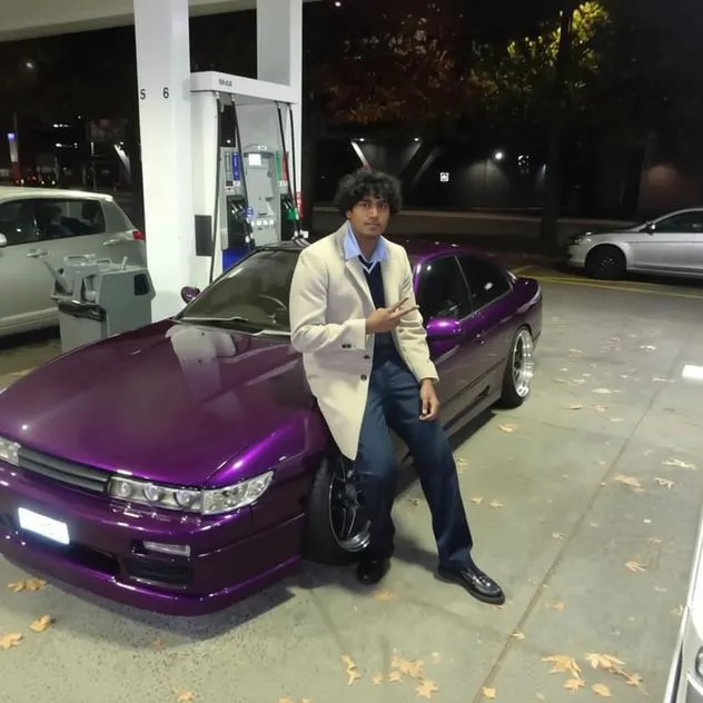 Manindra de Mel standing beside a car at a petrol station at night